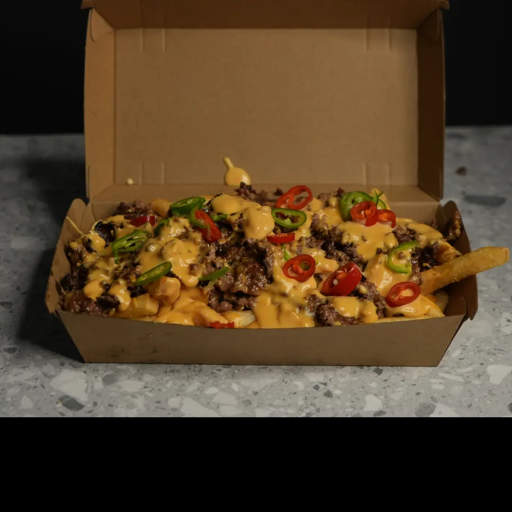 Smash Loaded Fries as shot: kraft box on a stone bench with the lid open